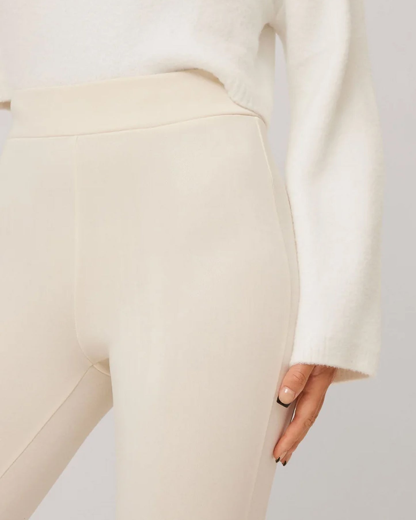 Black high waisted trouser leggings with faux leather look, worn with soft knitted cream jumper.