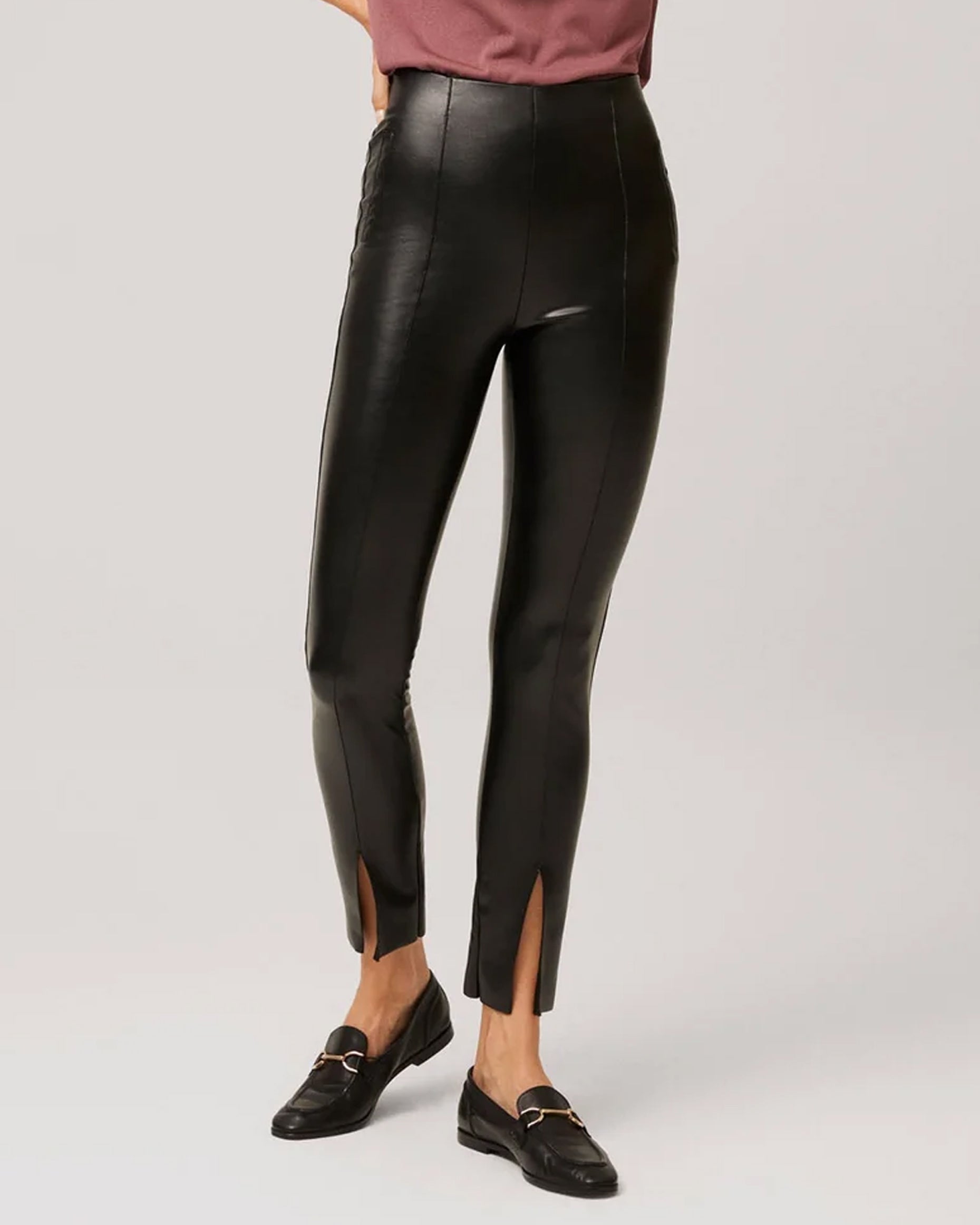 Ysabel Mora 70295 Faux Leather Slit Leggings - Tight fit faux leather thermal black coloured leggings with a warm plush fleece lining, faux side pocket stitching, centre seam down the front of the leg with a slit opening at the cuff, worn with black sneakers.
