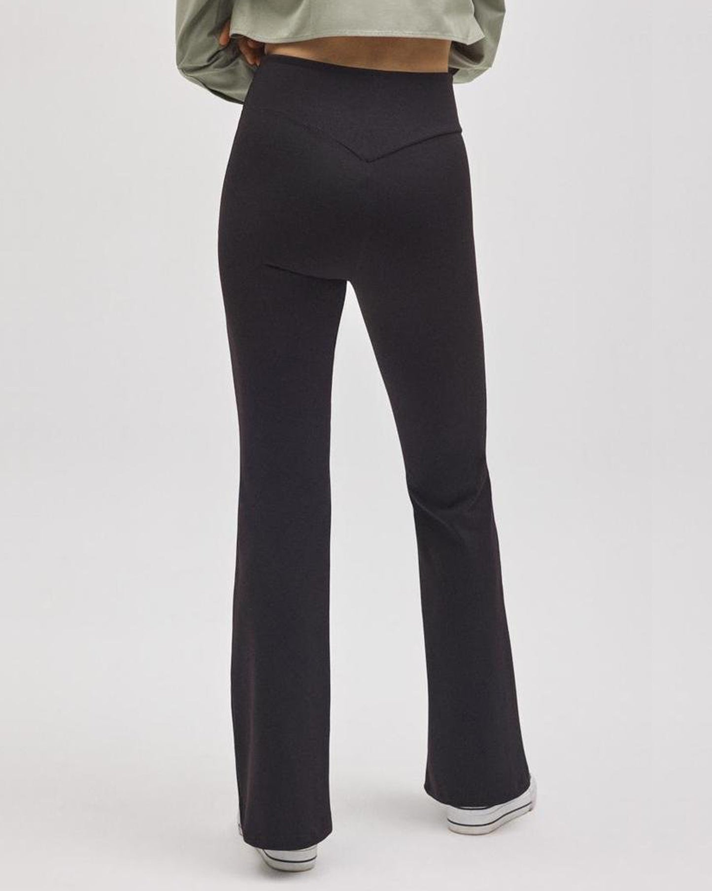 Black flared pants worn by a person on a white background, back view.