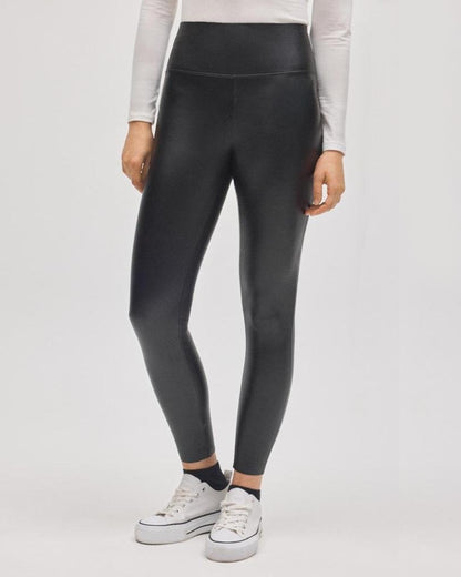 Black faux leather leggings worn with a white long sleeved top and white converse sneakers.