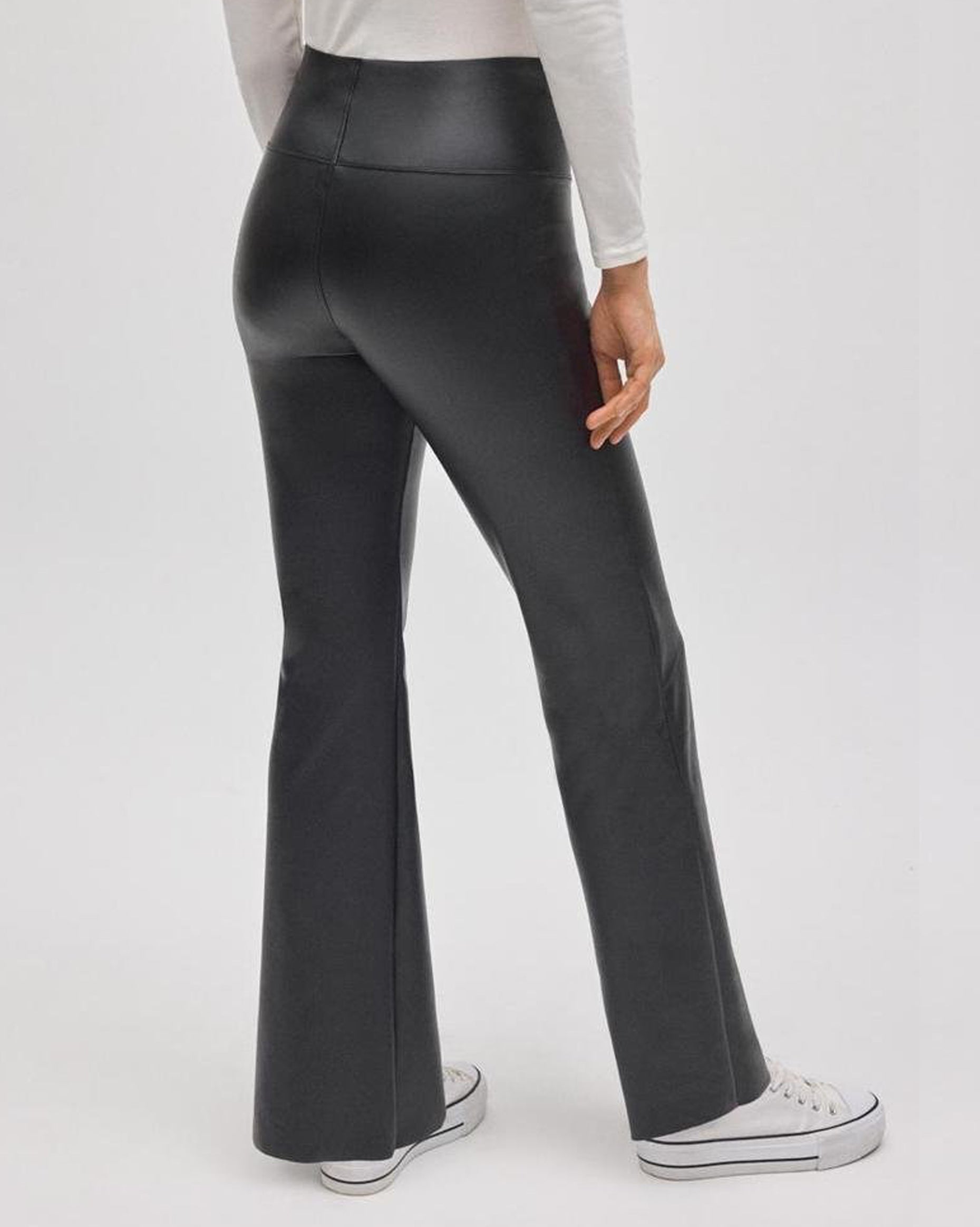 Black faux leather flared pants worn by a person on a white background, back view.