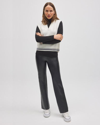 Woman wearing a black and white outfit with a vest on a light gray background