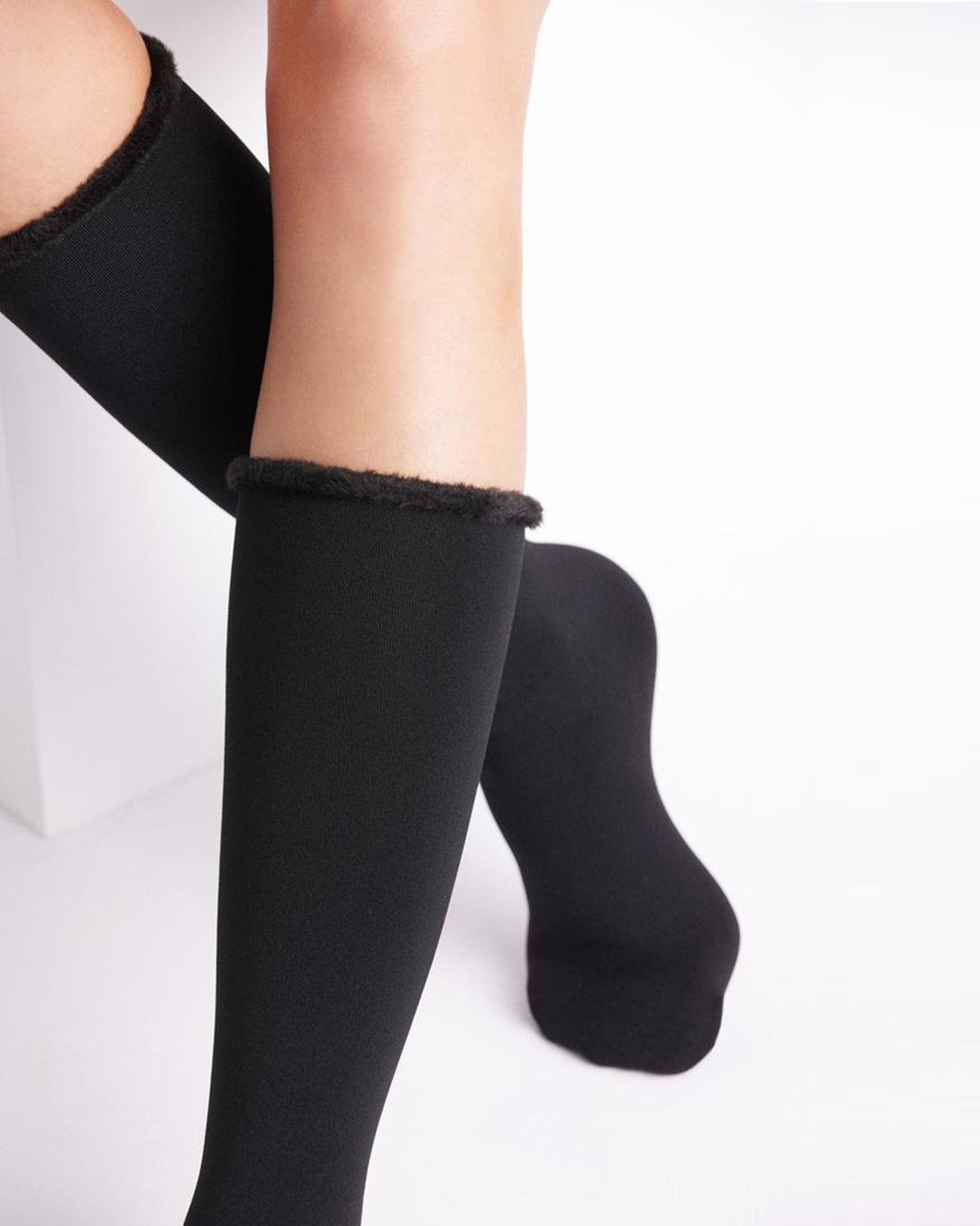 Black knee-high socks with textured trim worn by a person on a white background