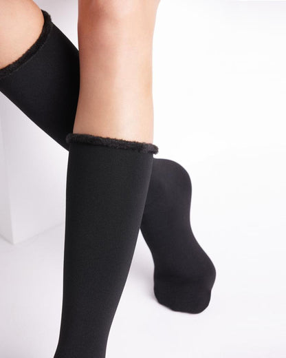 Black knee-high socks with textured trim worn by a person on a white background