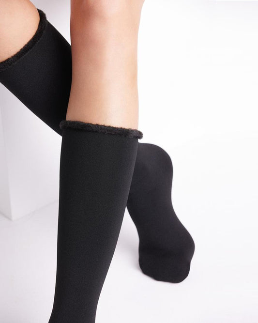 Black knee-high socks with textured trim worn by a person on a white background