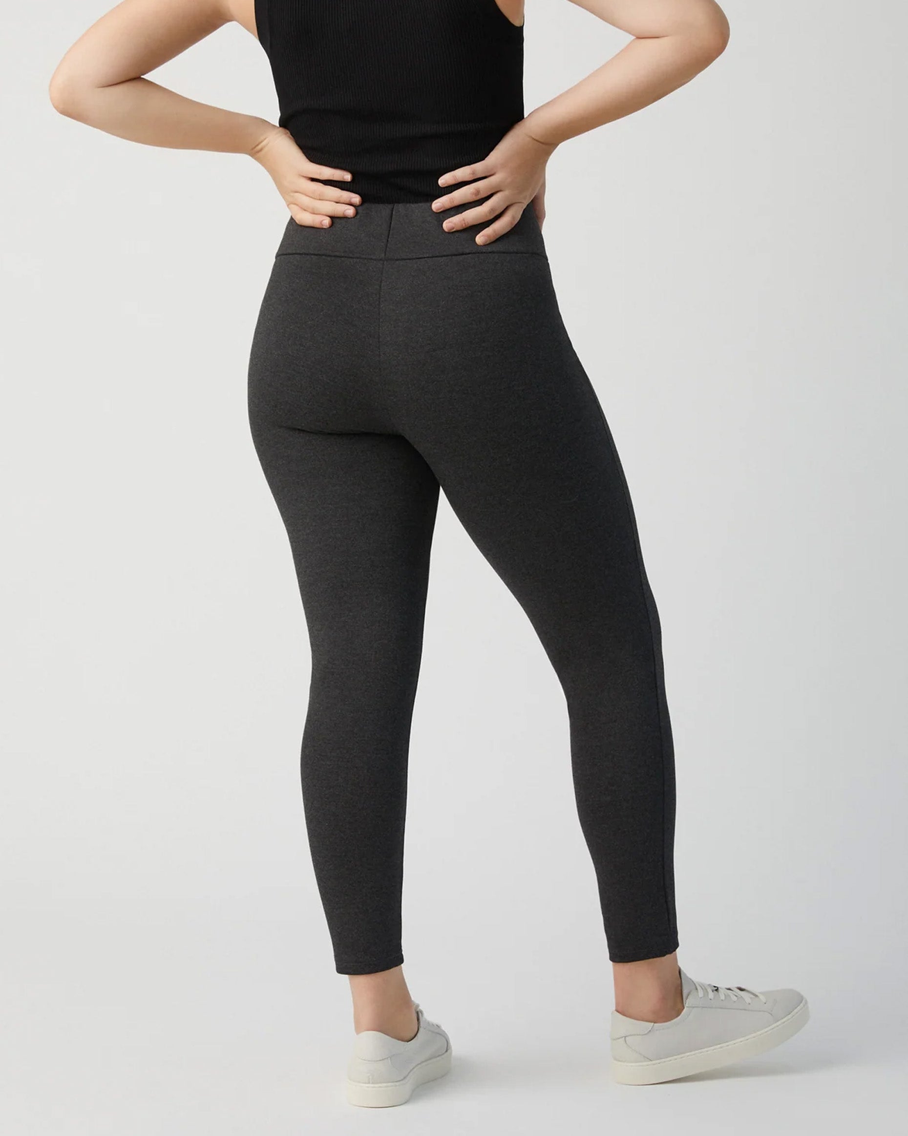 Ysabel Mora 70273 Leggings - Dark fleck grey jodhpur style high waisted leggings with silver side zips, raised centre seam down the leg and deep slimming waist band. Worn with black tank top and sneakers, back view.