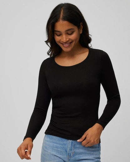 Woman wearing a black long-sleeve crew neck top and blue jeans on a grey background