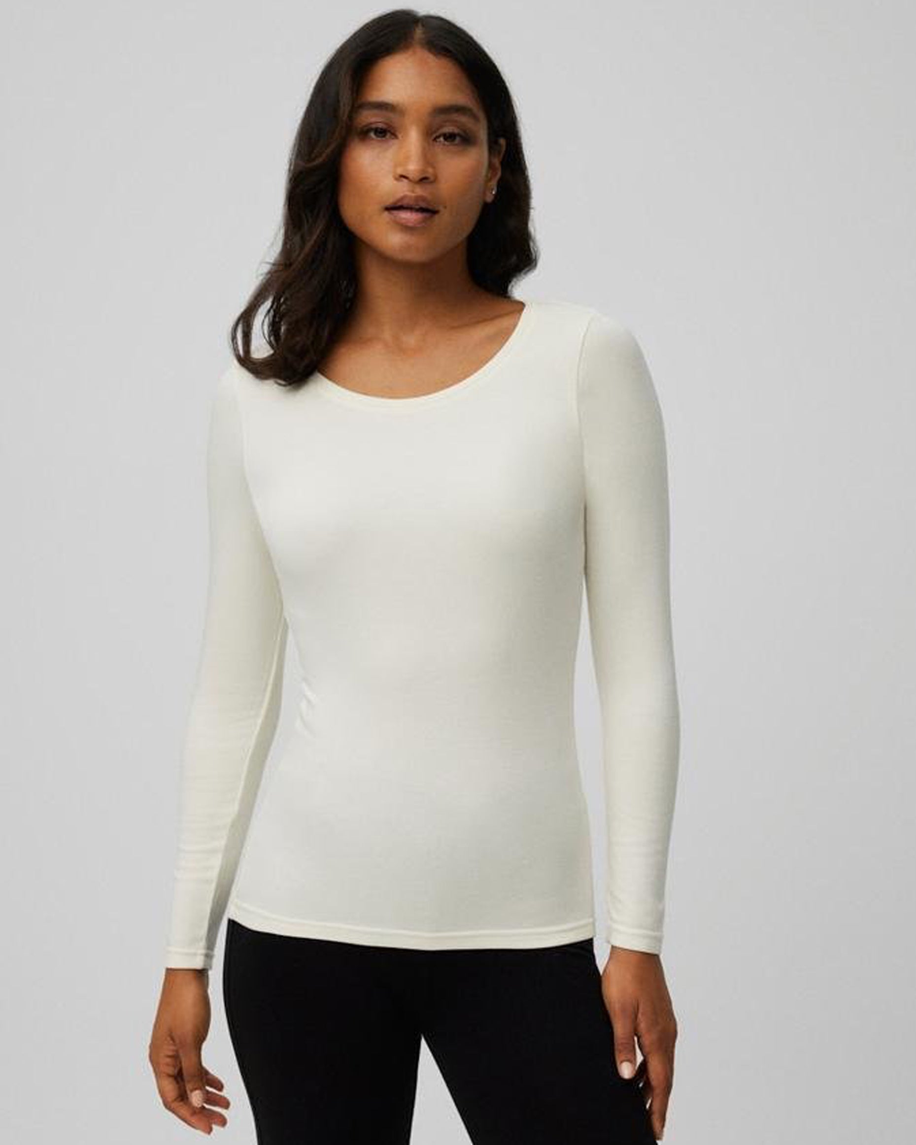 Woman wearing a cream long-sleeve crew neck top against a grey background