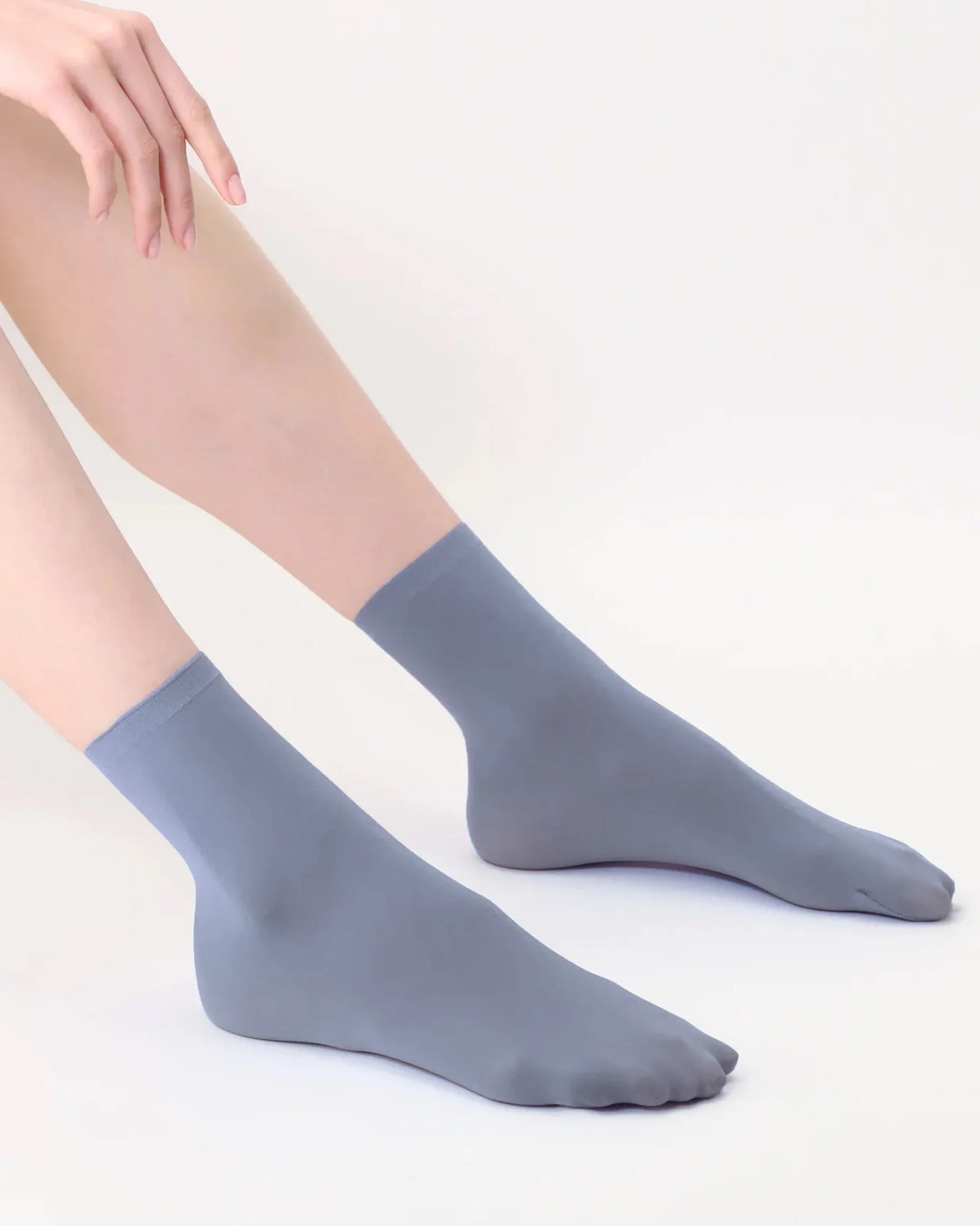 Grey blue socks worn by a person on a light grey background