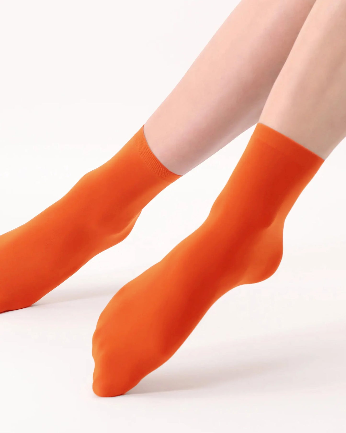 Orange socks worn by a person on a white background