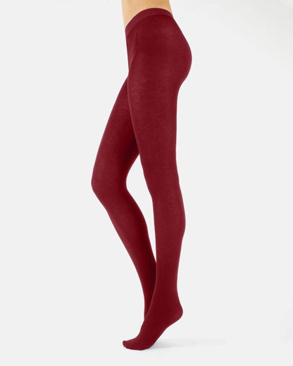 A side view of a model's legs wearing solid deep burgundy tights against a clean white background.