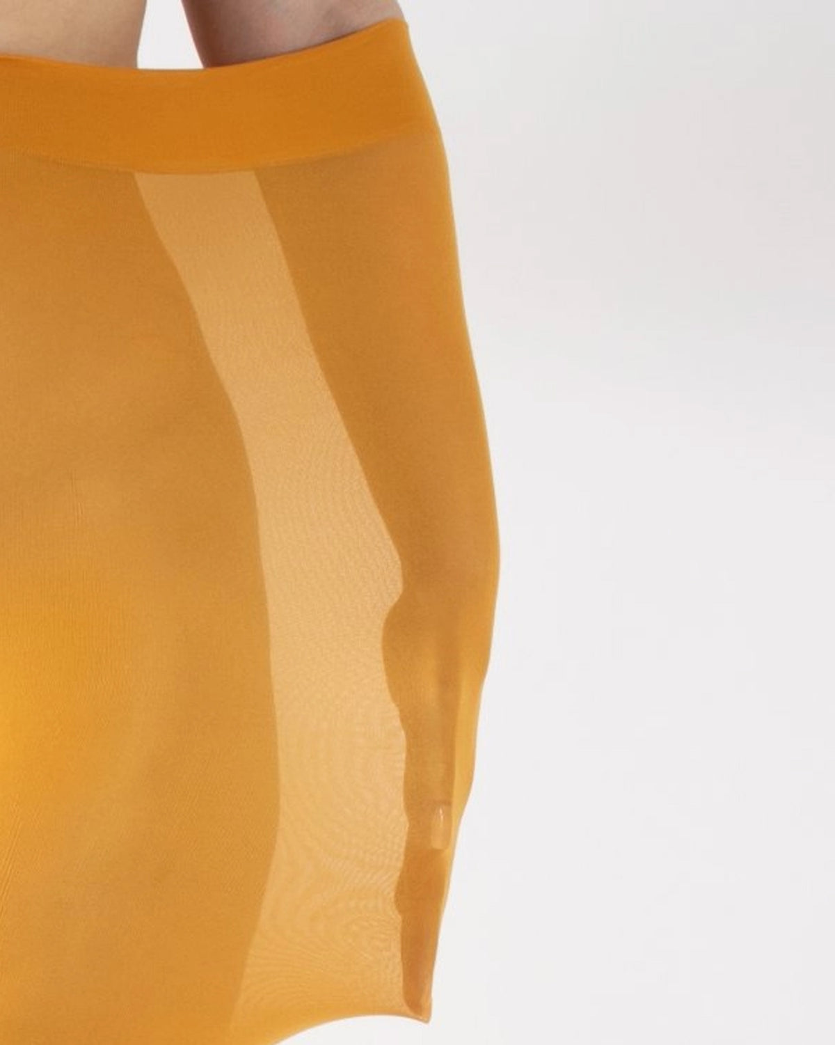 Close-up of an opaque mustard yellow tight worn by a model with their arm inside to demonstrate how stretchy they are