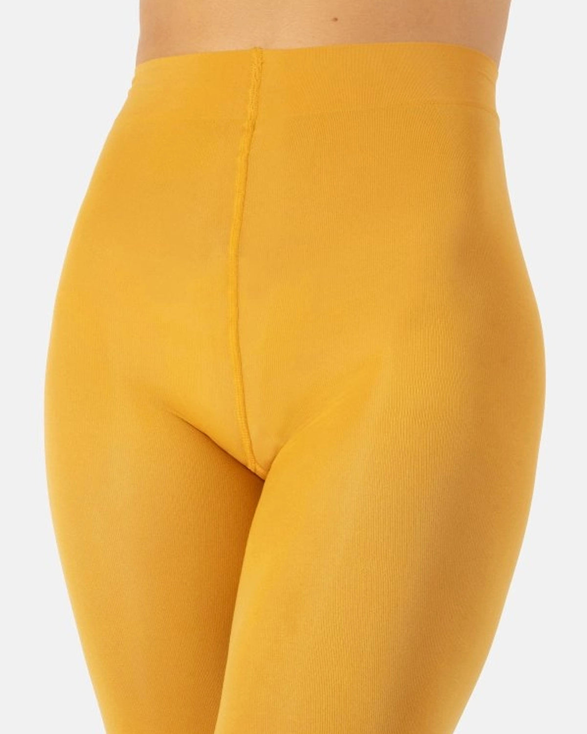 Close-up of a model wearing high-waisted, solid mustard yellow leggings against a light gray background.