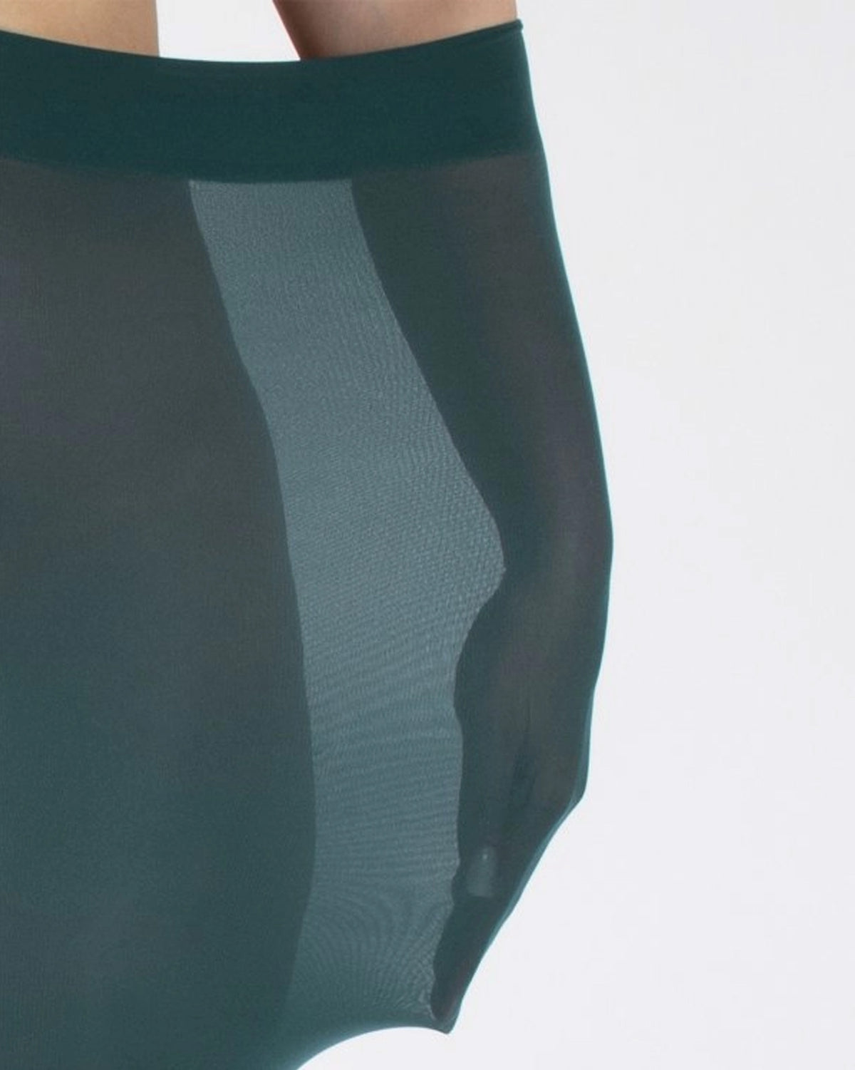 Close-up of an opaque teal green tight worn by a model with their arm inside to demonstrate how stretchy they are