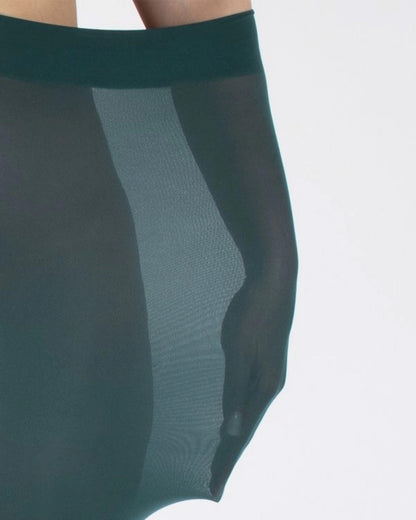 Close-up of an opaque teal green tight worn by a model with their arm inside to demonstrate how stretchy they are