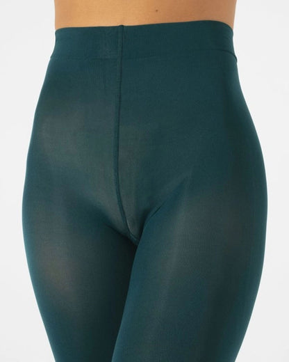 Close-up of a model wearing high-waisted, semi-sheer dark teal tights against a light gray background.