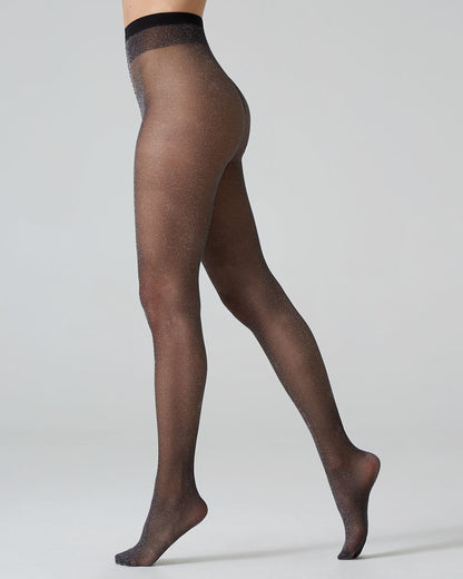 Black sheer tights with sparkly silver lamé worn by a person on a light grey background