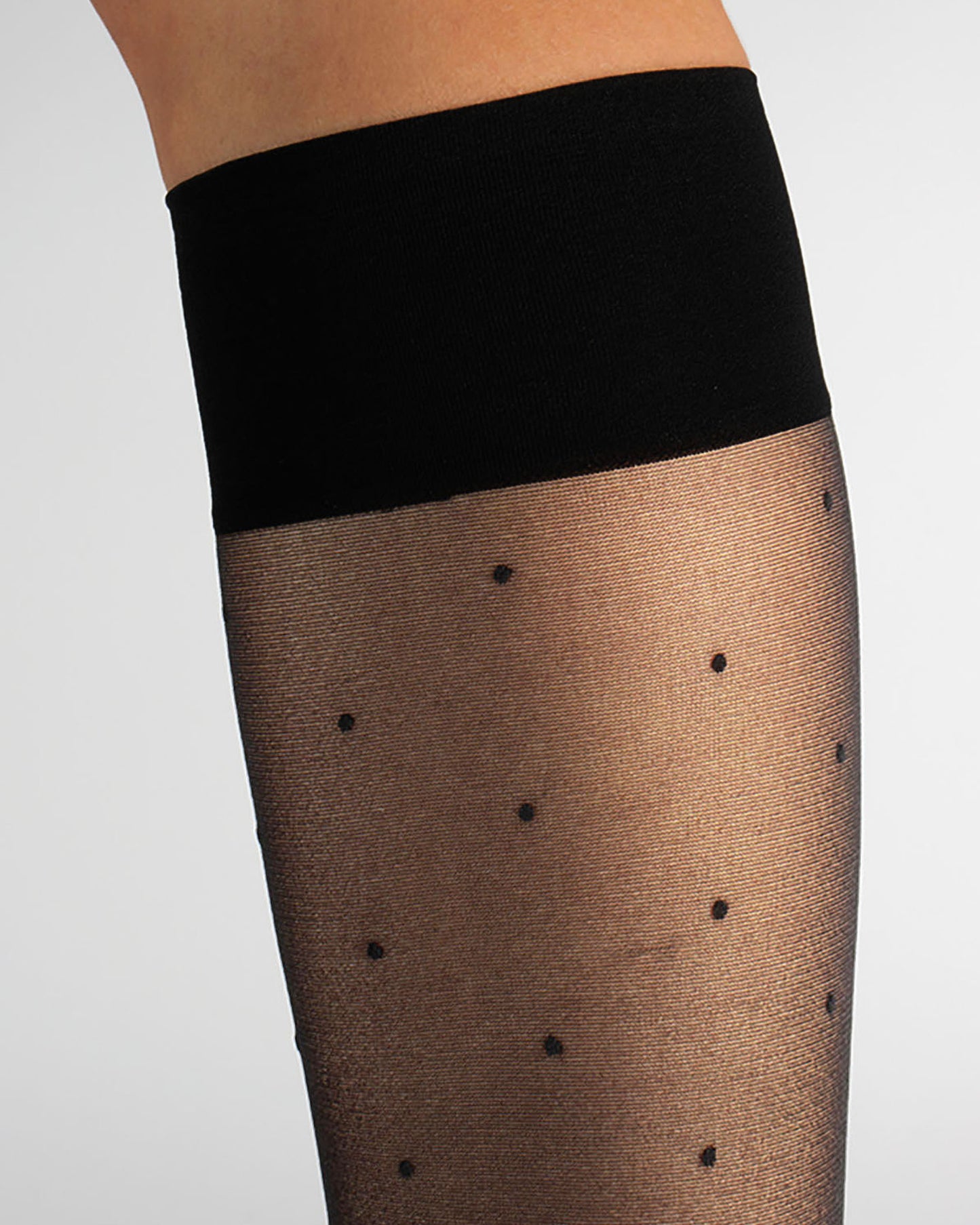Black knee-high socks with black polka dots and a black cuff on a white background
