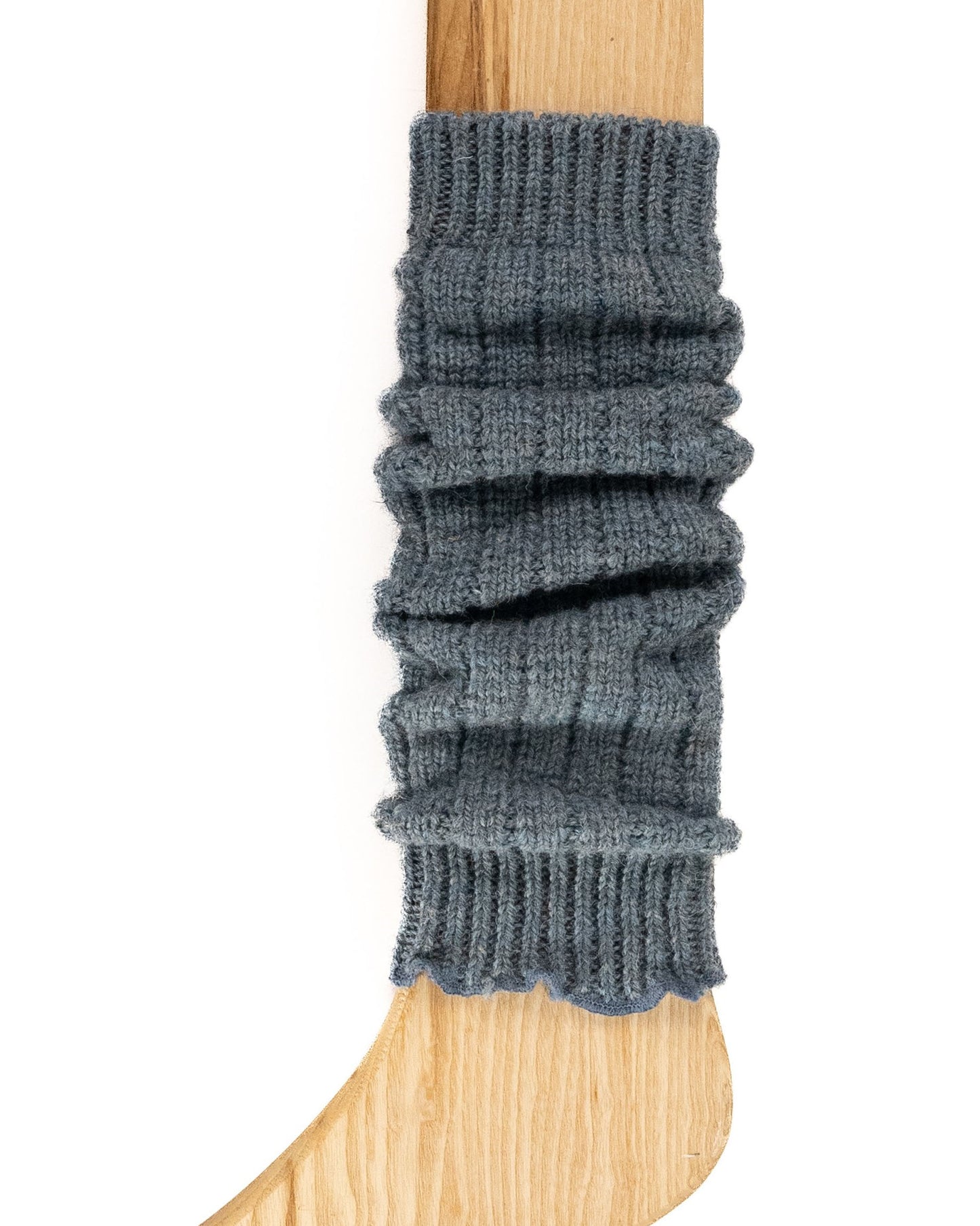 A pale denim blue chunky ribbed knitted leg warmer displayed on a wooden model.