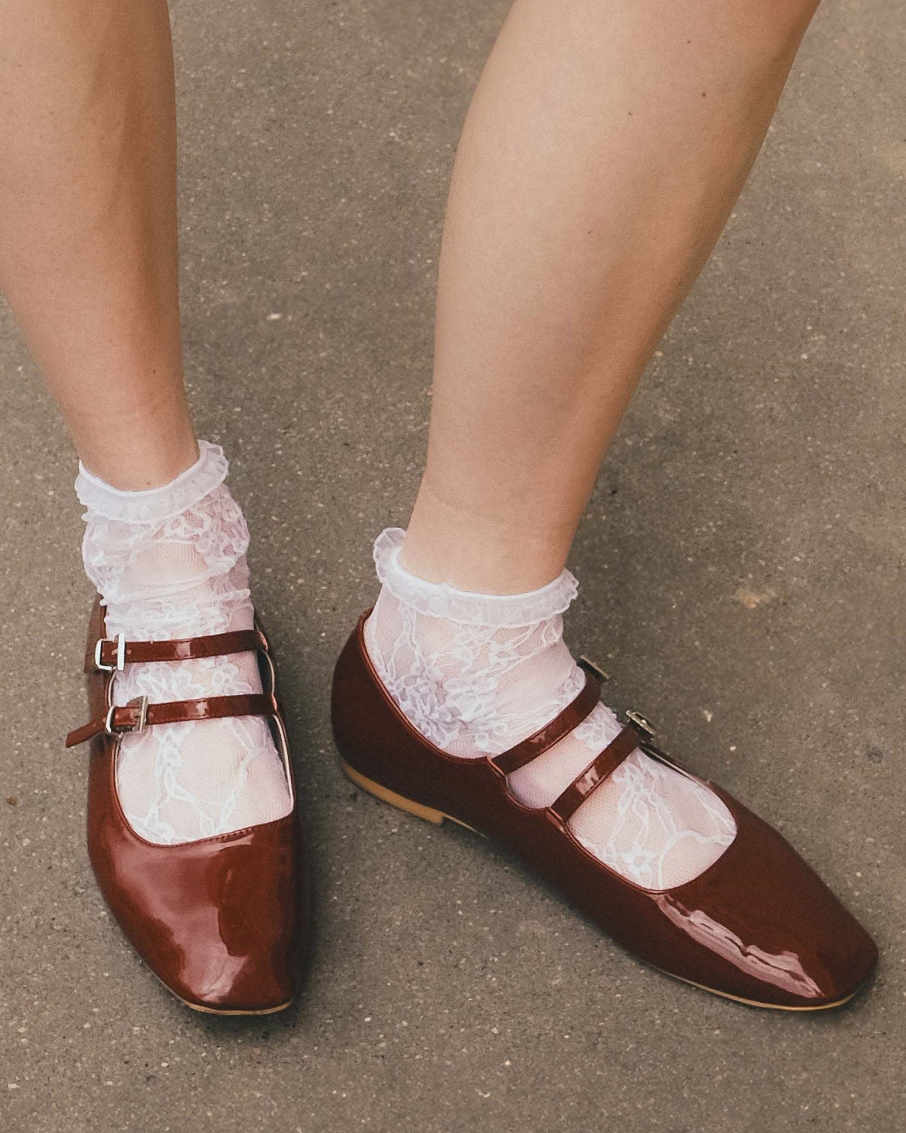 Burgundy shoes with white laces worn on a concrete surface
