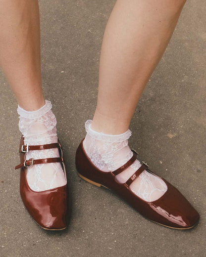 Burgundy shoes with white laces worn on a concrete surface