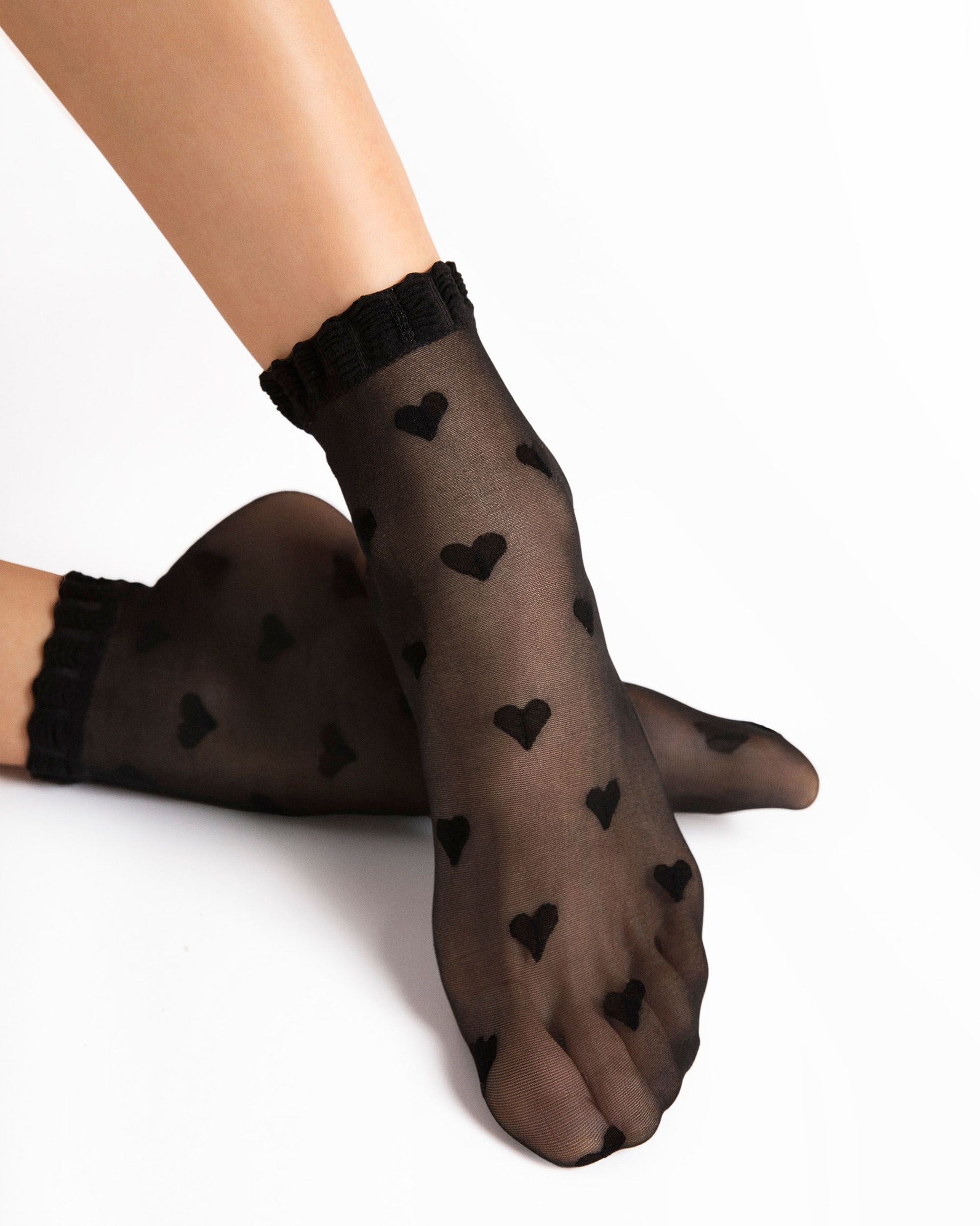Black heart-patterned sheer socks worn by a person on a white background