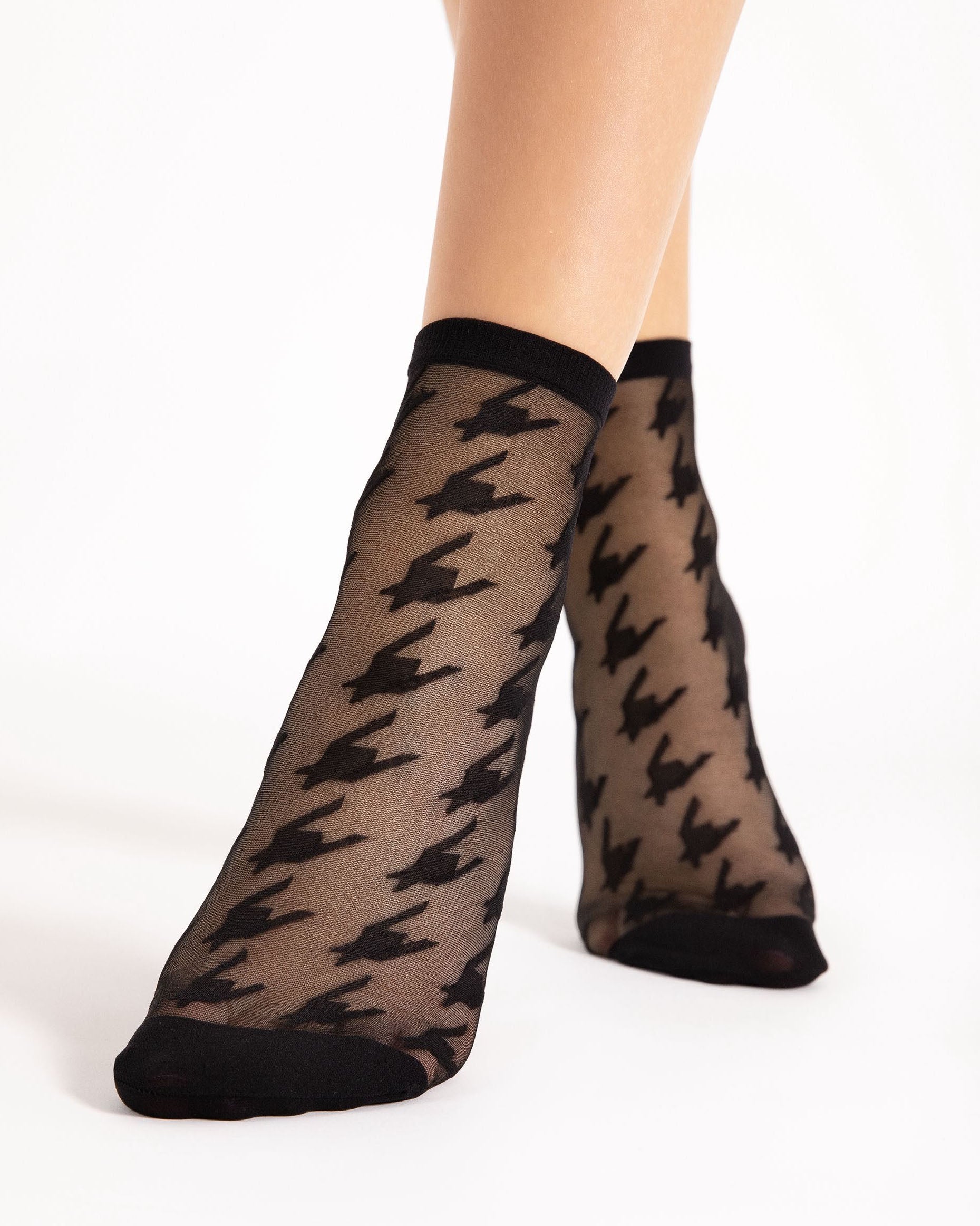 Sheer black houndstooth patterned socks with black cuffs and toes on a white background