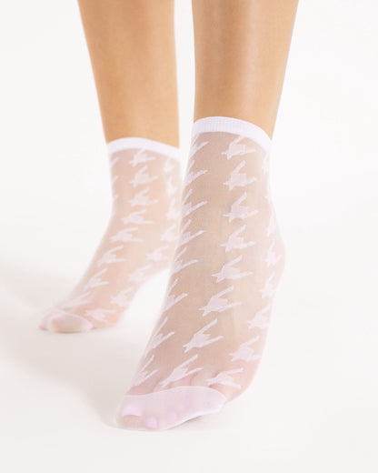 Sheer white houndstooth patterned socks with plain cuff and toes on a white background