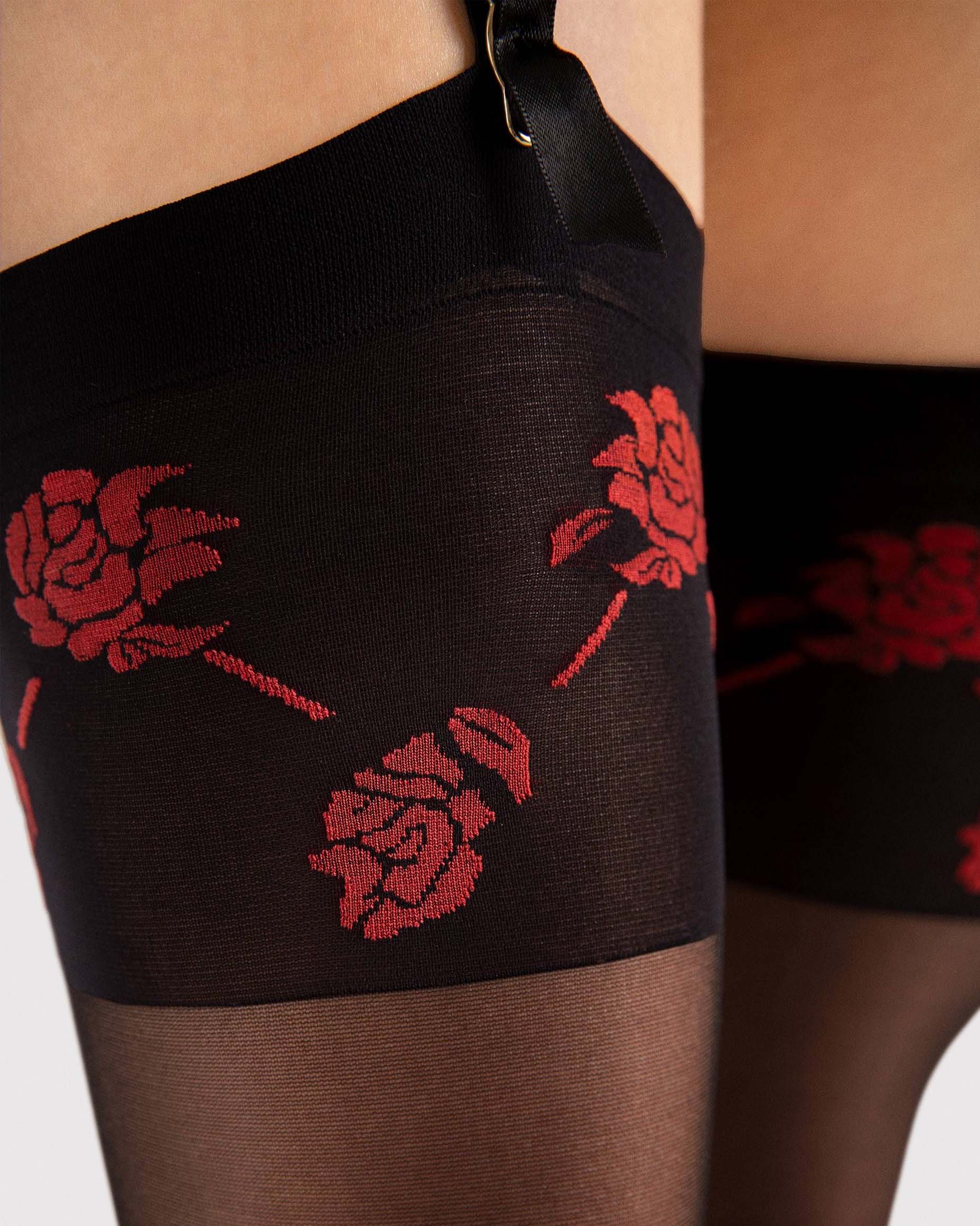 Black stockings with red rose pattern worn by a person.