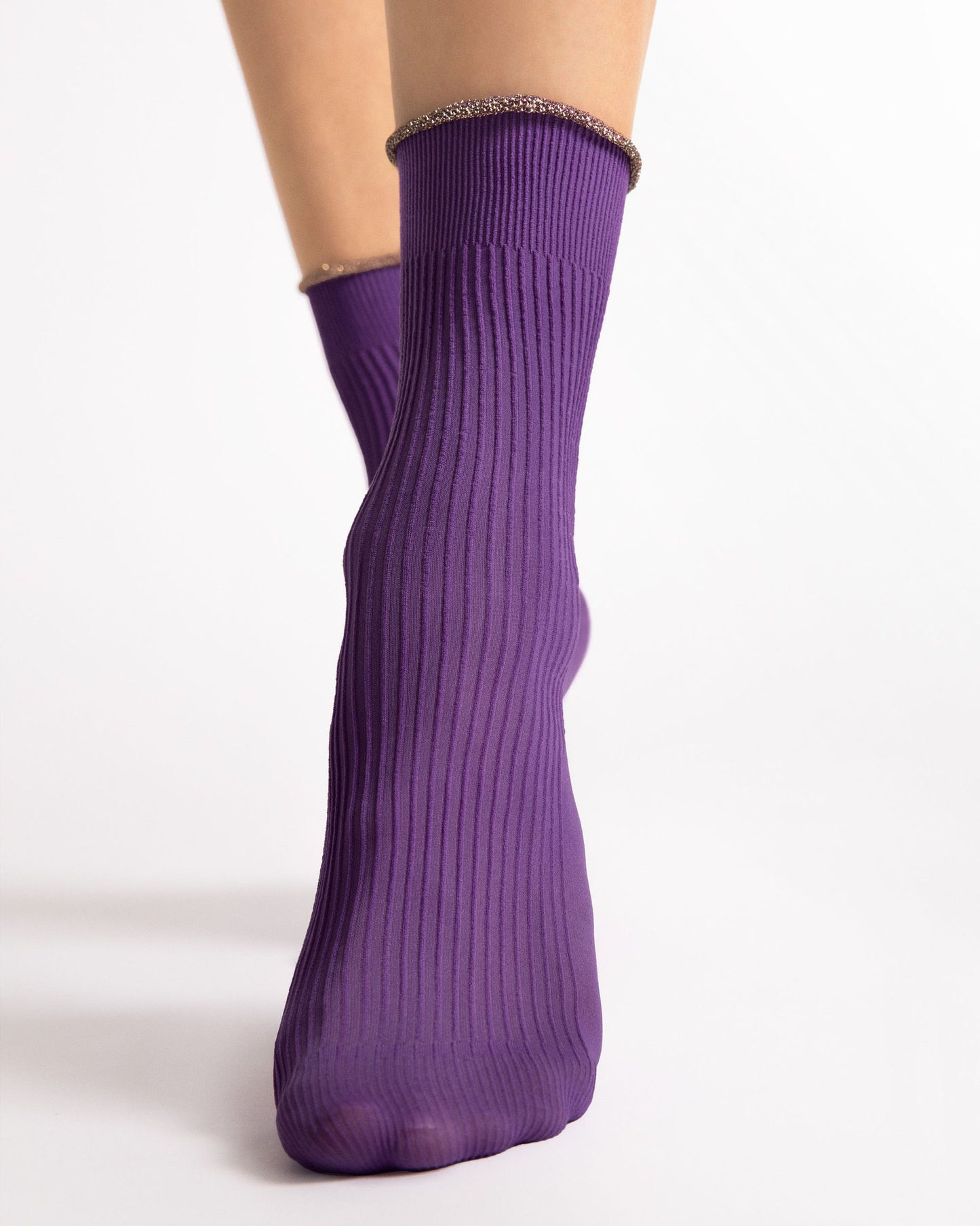 Purple socks with a textured top worn by a person on a white background