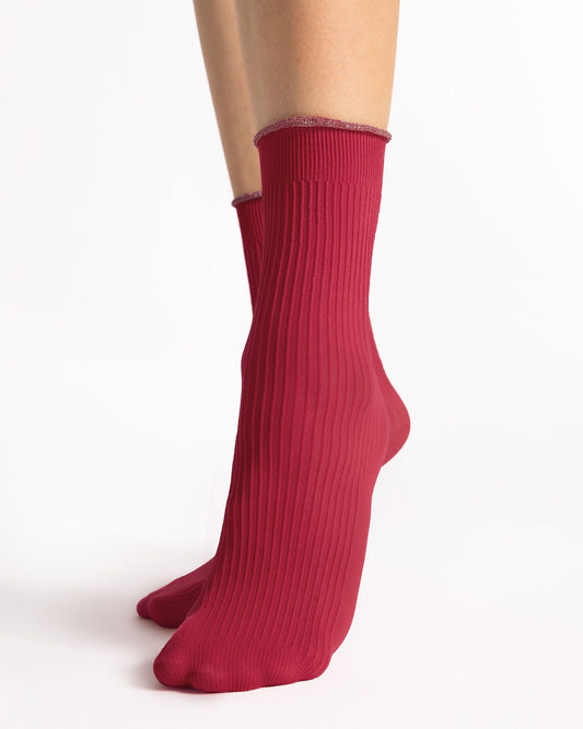 A pair of ribbed crew socks in a deep berry red color, worn on a model's feet against a clean white background.