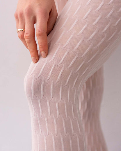 Close-up of a person wearing pale pink tights with a subtle pattern on a light background.
