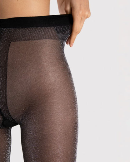 Sheer black tights with silver shimmer worn by a person on a light grey background