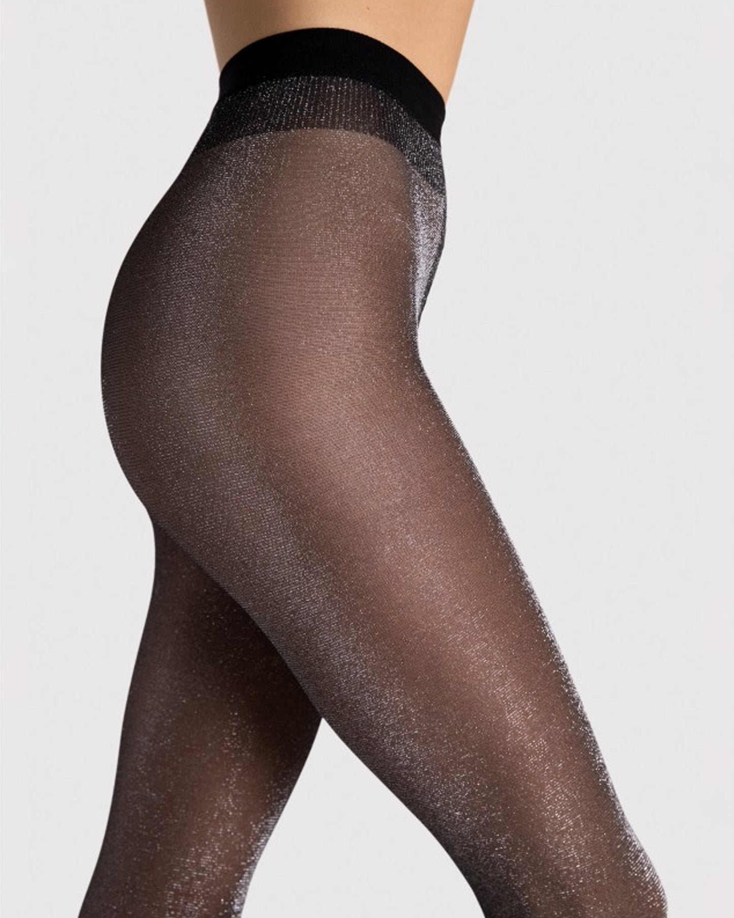 Black sheer tights with silver glitter worn by a person on a light grey background