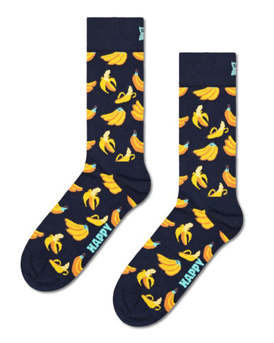A pair of navy blue crew socks with a repeating pattern of yellow bananas and the word 'HAPPY' printed in light blue near the foot, displayed against a plain white background.