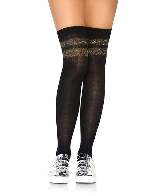 Black thigh-high sheer socks with two horizontal glittery gold bands near the top, shown on a model's legs paired with silver sneakers against a white background.