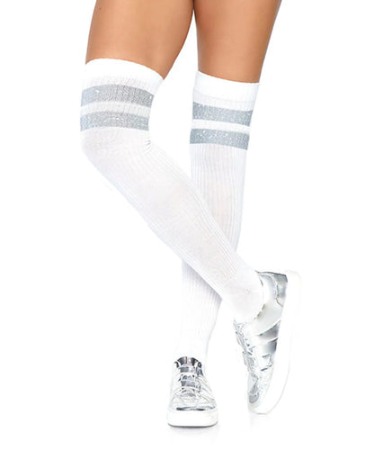 White ribbed knee-high socks with two horizontal silver glitter stripes near the top, worn on a model's legs with silver sneakers against a white background.