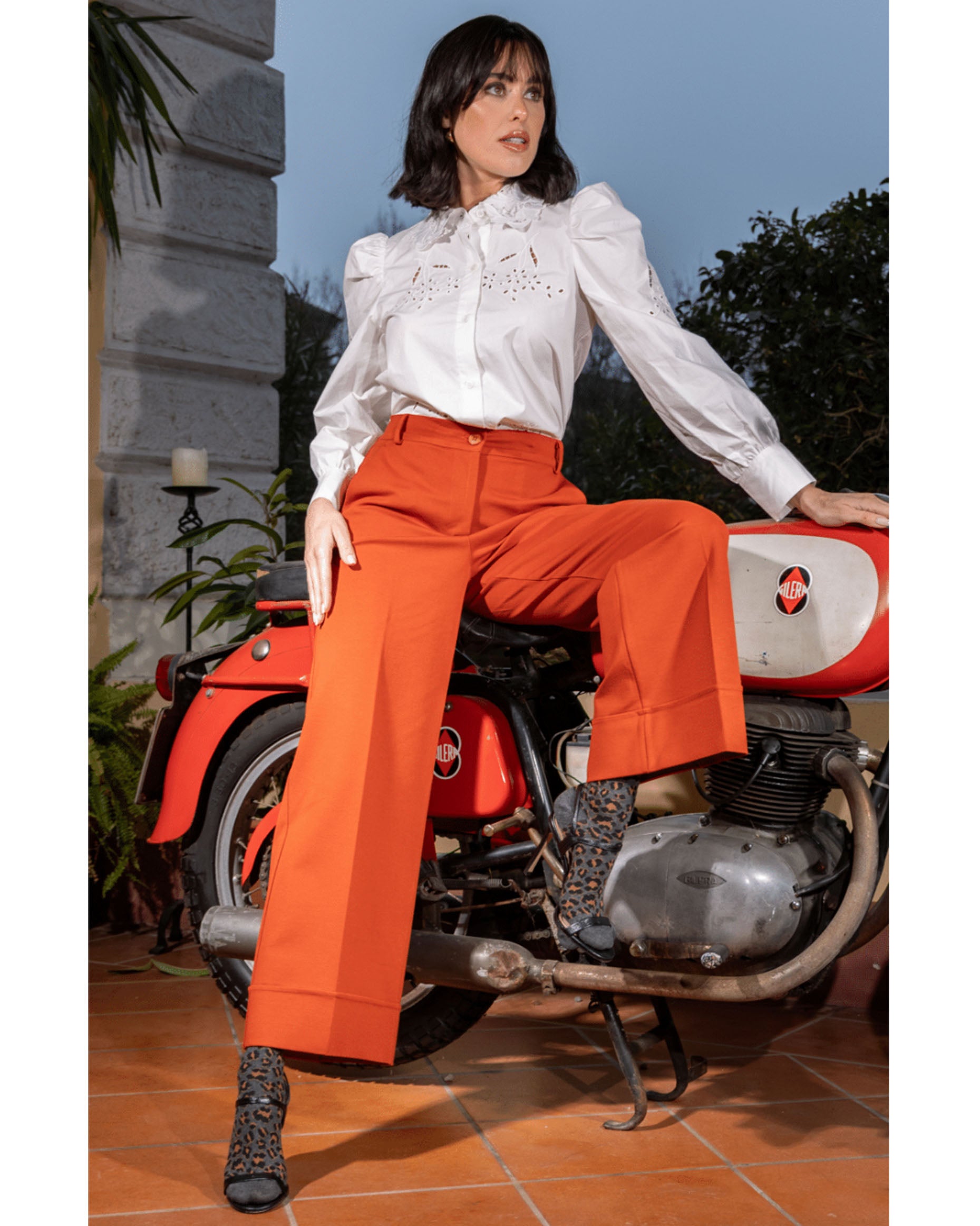 Grey cotton crew length socks with a leopard print pattern, worn with black strappy high heels and orange wide leg pants and white blouse.