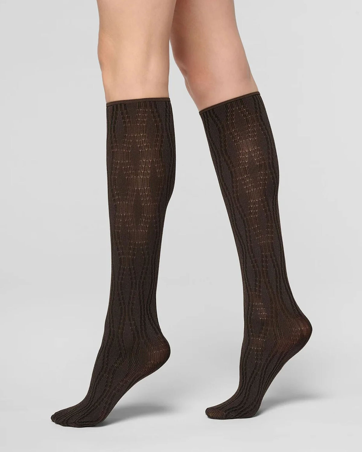 A pair of dark brown ribbed knee-high socks worn on legs, shown against a light gray studio background.