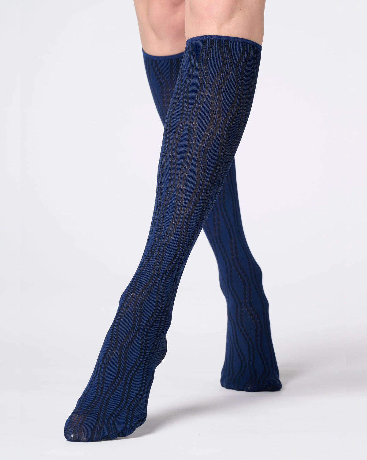 A pair of navy blue knee-high ribbed socks with a subtle gold grid pattern, shown on a model's legs against a light gray studio background.