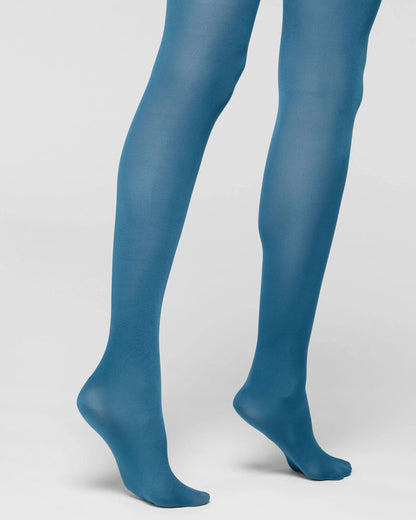 A pair of sheer, semi-transparent blue tights worn on a model's legs, shown from the mid-thigh down against a light gray studio background.