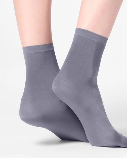 A pair of crew-length gray socks worn on feet, shown against a clean light gray studio background.