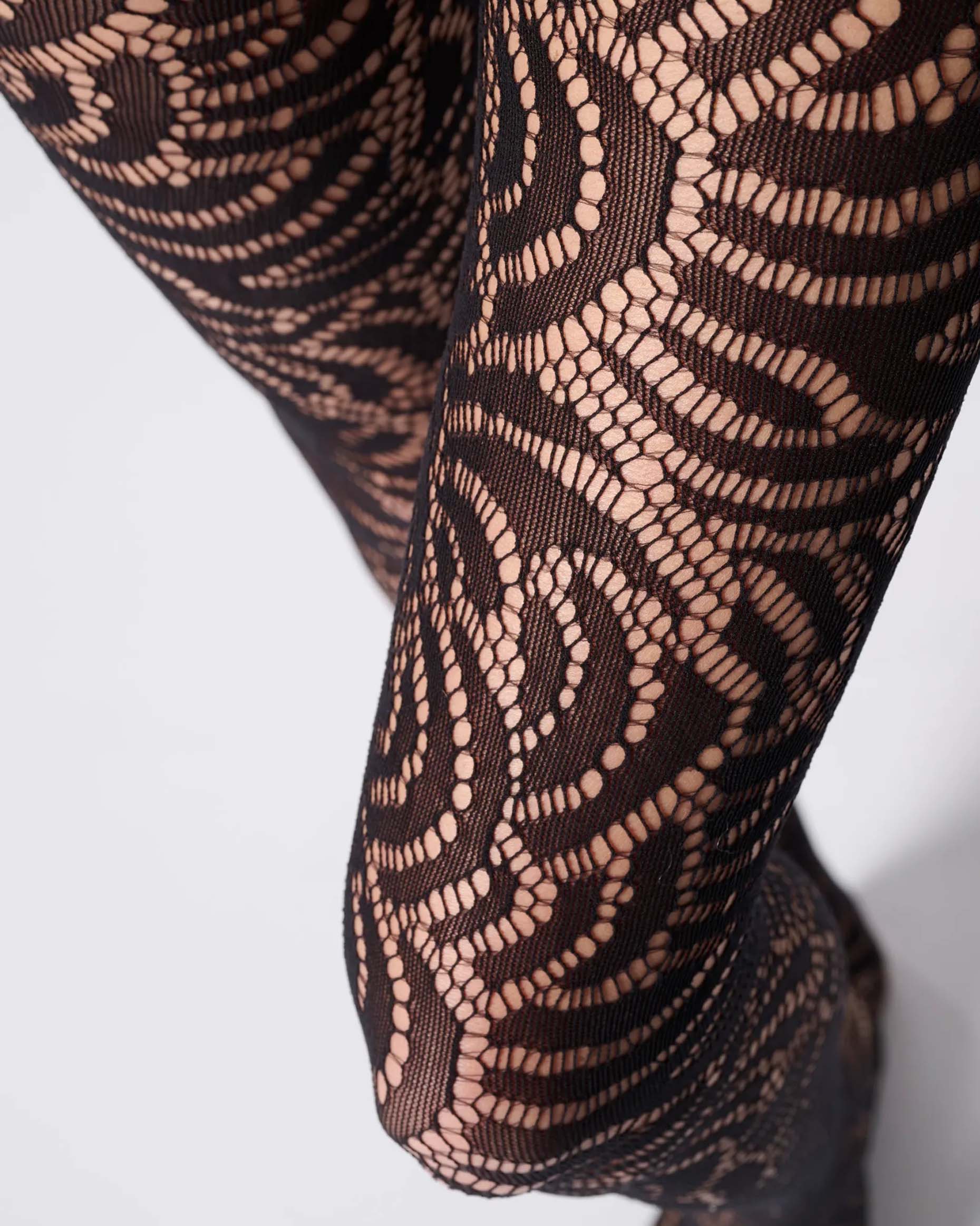 Soft black openwork floral lace style tights close up detail.