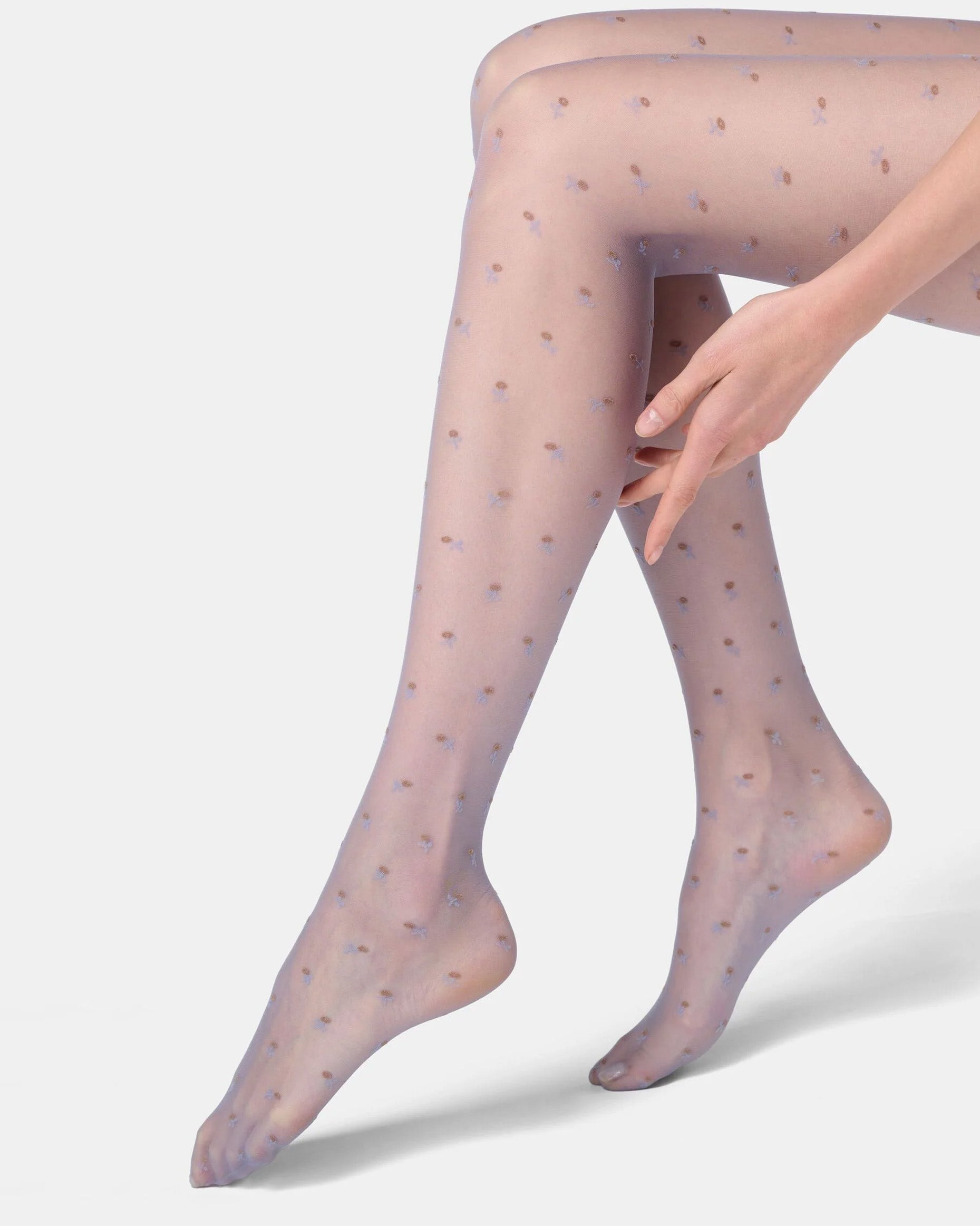 Sheer light blue tights with subtle flower pattern worn by a person on a light grey background