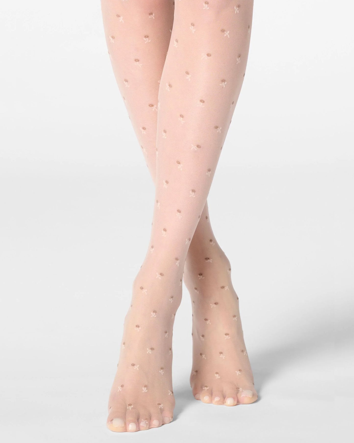 Sheer nude tights with small floral pattern worn by a person on a light grey background