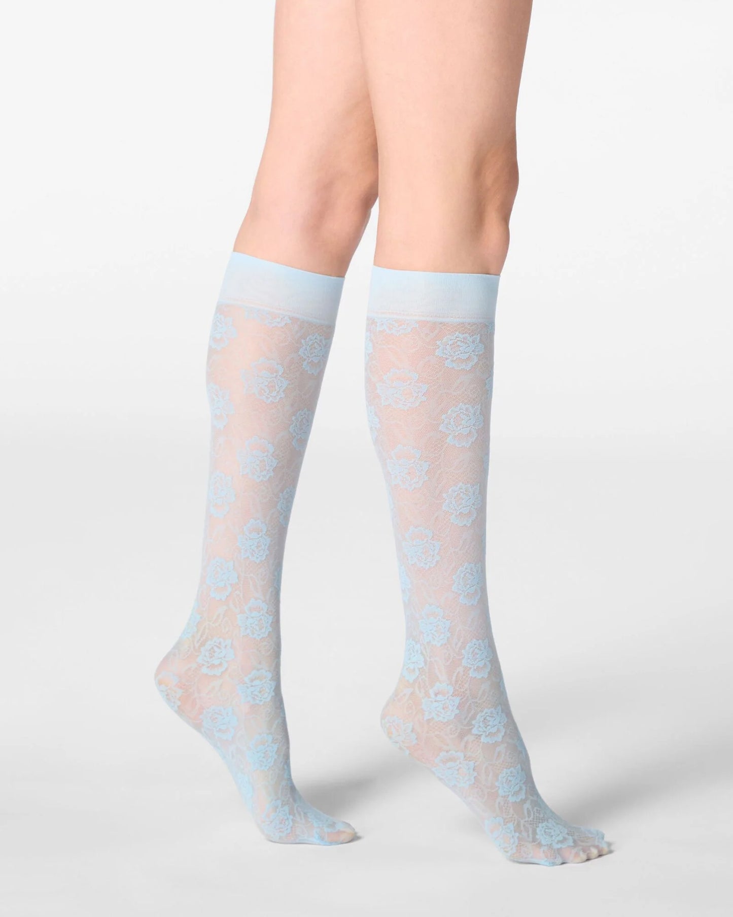 Sheer light blue socks with a floral lace pattern worn by a person on a white background