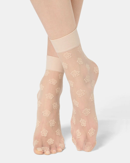 Sheer beige floral-patterned socks worn by a person on a white background