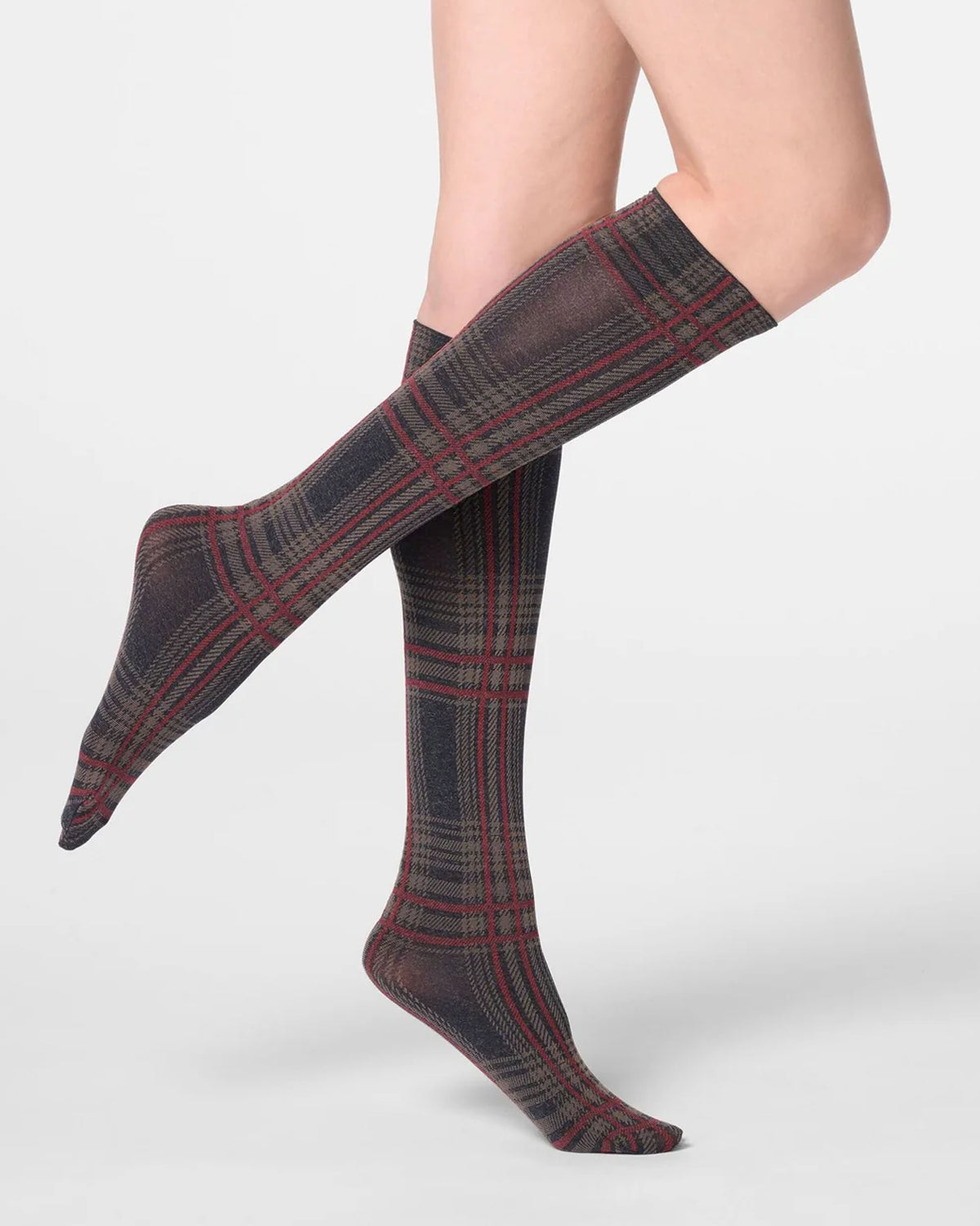 A pair of knee-high socks with a dark gray and black tartan plaid pattern accented by red and green stripes, shown on a model's legs against a light gray background.