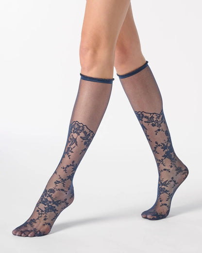 Sheer navy blue knee-high socks with a floral lace pattern from the toe to the calf and a narrow cuff with ruffles.