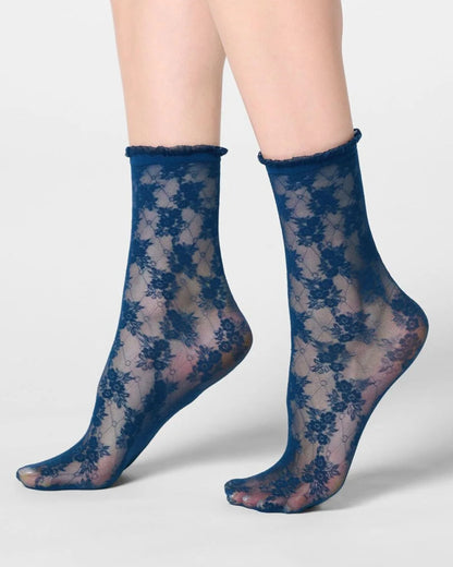 A pair of sheer navy blue lace ankle socks with a floral pattern, shown on a model's feet against a light gray background.